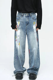 Painterly wash wide-leg denim trousers in medium blue with artistic paint splatters and a relaxed fit.