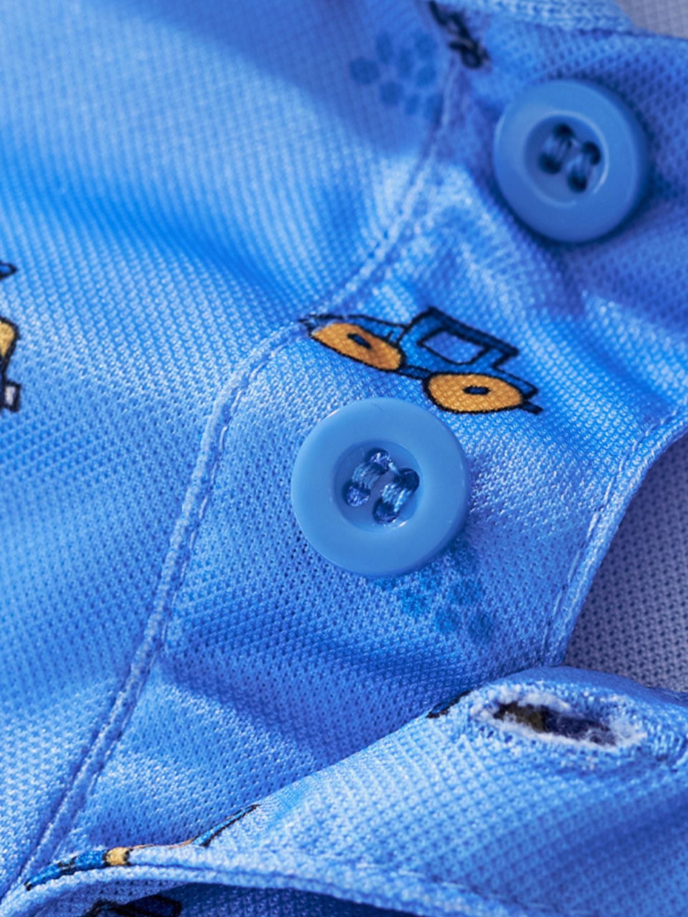 Blue toddler polo shirt with excavator print and blue buttons.