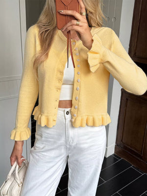 Pastel yellow acrylic knit cardigan with ruffled trim and buttons.