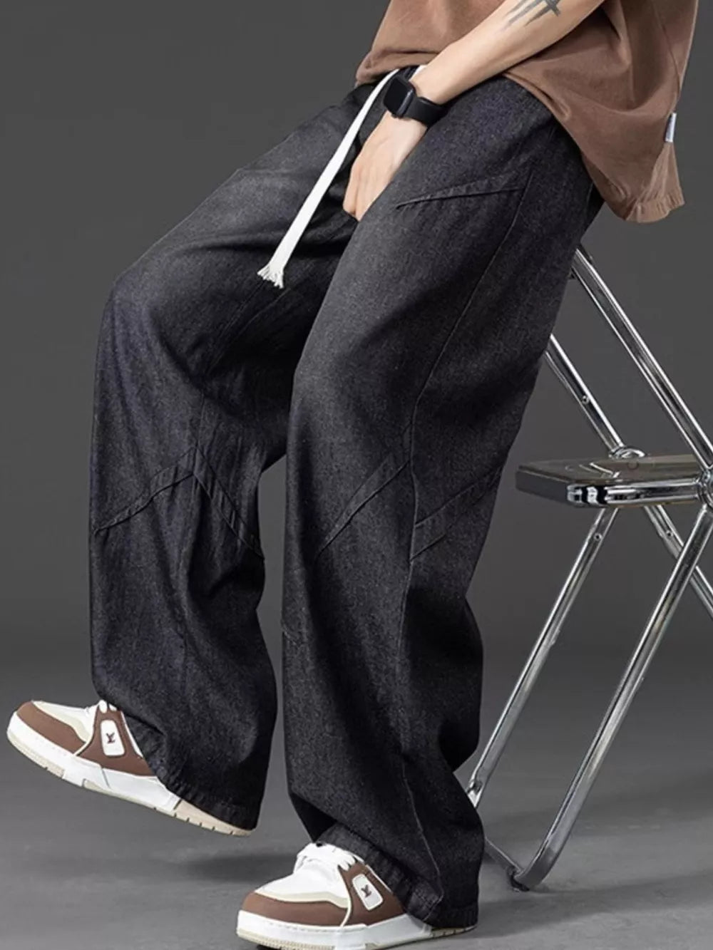 Men's oversized black denim jeans with adjustable drawstring waist and unique seam details.