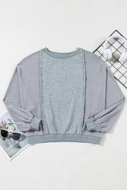 Gray waffle knit top with fringe trim and crew neck.