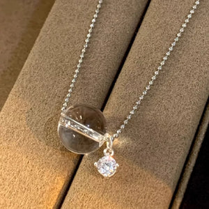Luminous crystal pendant necklace in silver with a clear orb and a diamond accent.