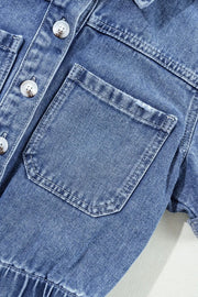 Medium wash denim romper with button-down front and chest pockets.