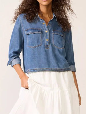 Blue denim cropped half snap top with two chest pockets and rolled sleeves.