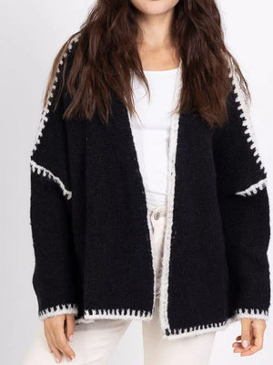 Black oversized cardigan with white contrast trim and stitching detail.