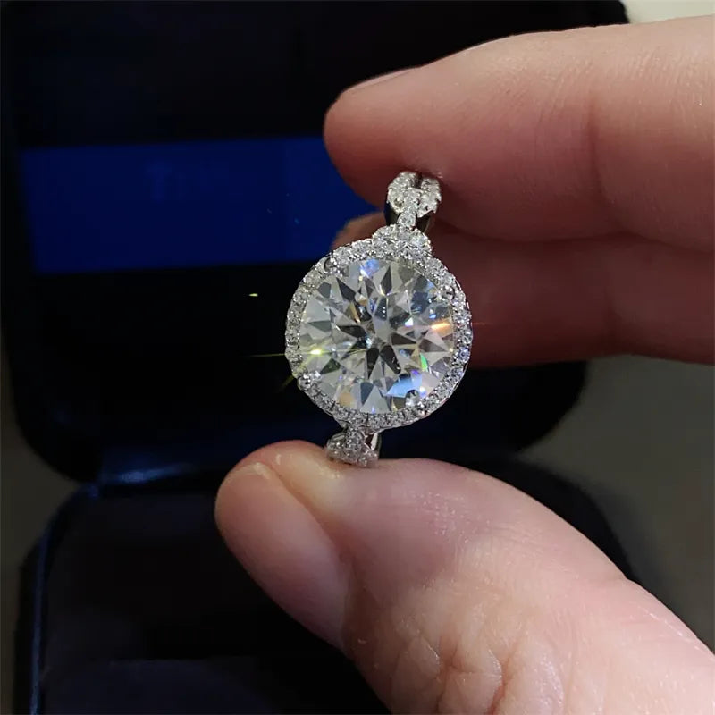 Silver moissanite engagement ring with halo and twisted band detail.