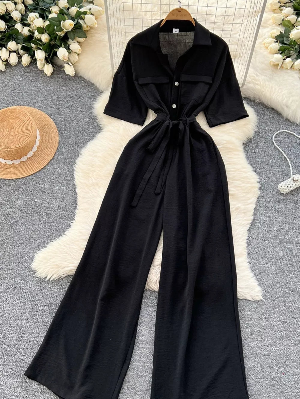 Black belted wide-leg maternity jumpsuit with pockets and button details.