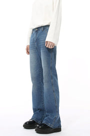 Medium wash denim jeans with pockets and a relaxed fit, styled with a white long-sleeve shirt.