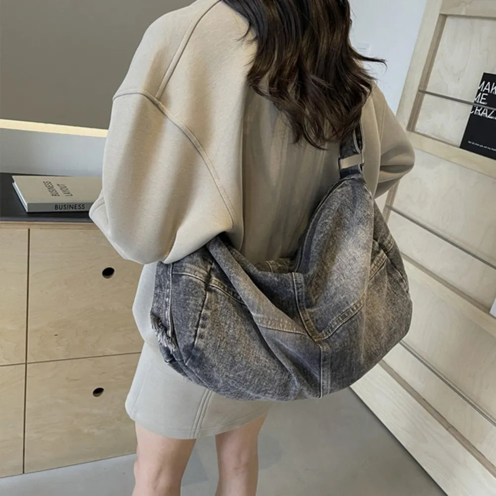 Washed denim hobo bag in medium gray with a slouchy silhouette and distressed details.