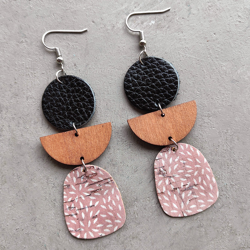 Geometric layered leather and wood earrings in dusty pink with white pattern, black, and wood.