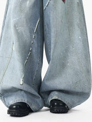Oversized light wash denim jeans with pearl accents and paint splatters.