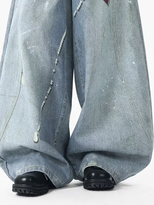 Oversized light wash denim jeans with pearl accents and paint splatters.
