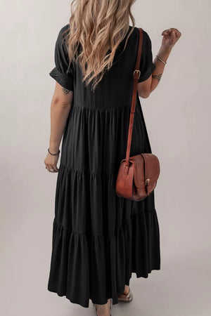 Black tiered maxi dress with short sleeves and a hidden placket, styled with a brown crossbody bag.