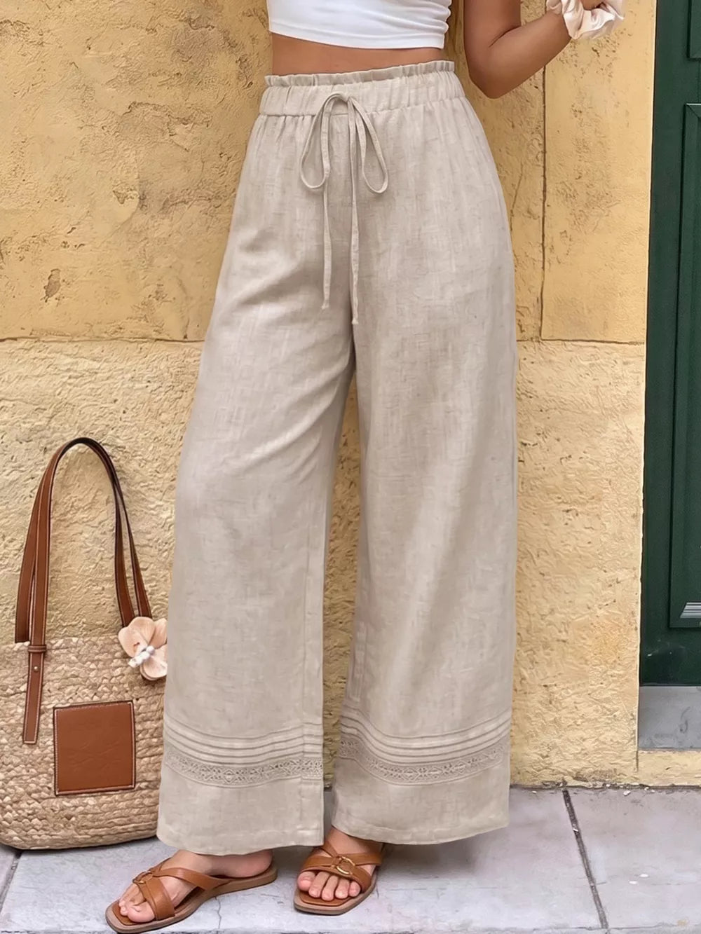 Beige wide-leg maternity trousers with drawstring waist and lace trim detail.