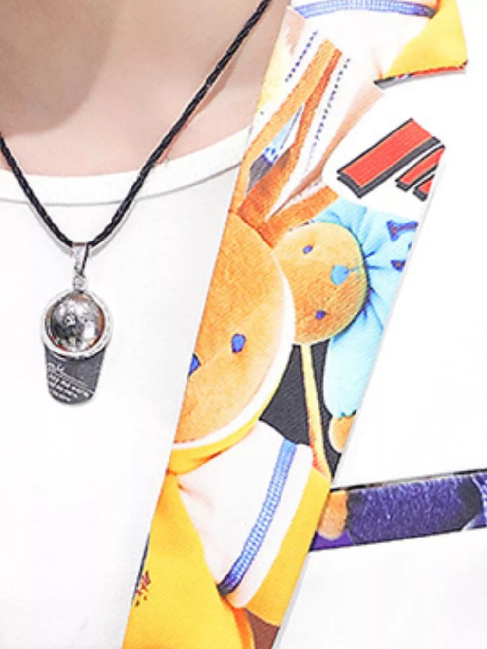 Men's blazer with vibrant printed trim and a silver pendant necklace.