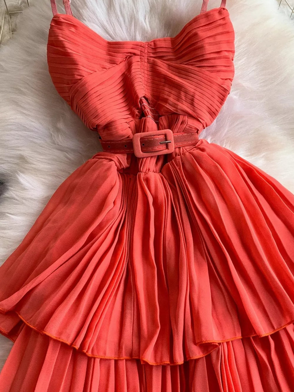 Coral belted midi dress with spaghetti straps, pleated bodice and tiered skirt.