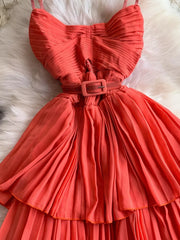 Coral belted midi dress with spaghetti straps, pleated bodice and tiered skirt.