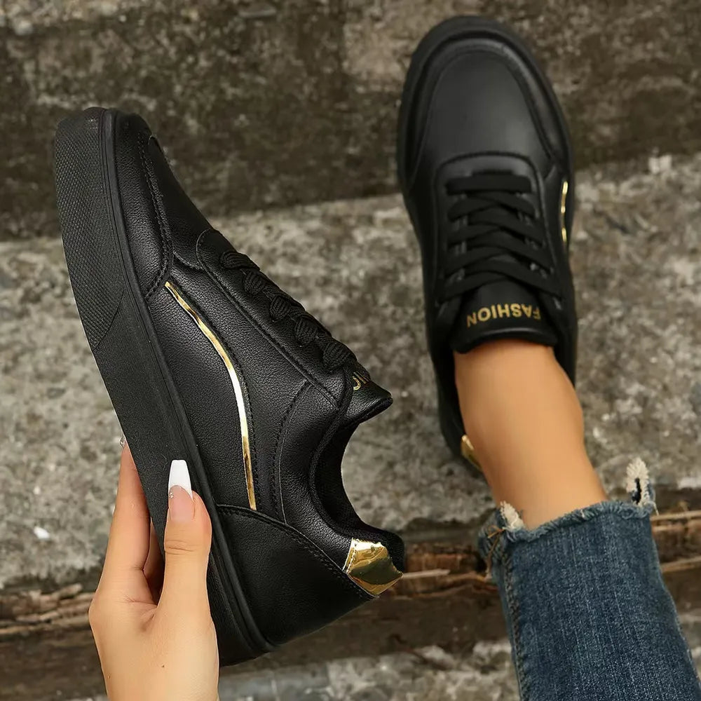 Black sneakers with gold metallic trim and laces.