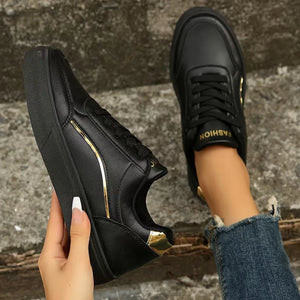Black sneakers with gold metallic trim and laces.