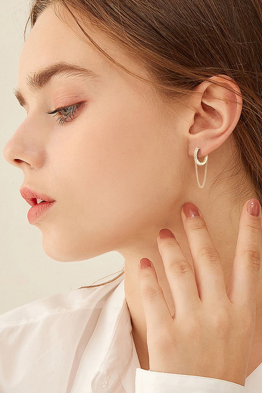 Gold dangling chain pavé huggie earrings with delicate chain detail.