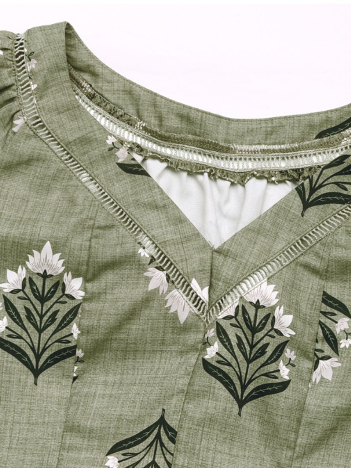 Botanical print V-neck blouse in matcha green with decorative trim and a textured fabric.