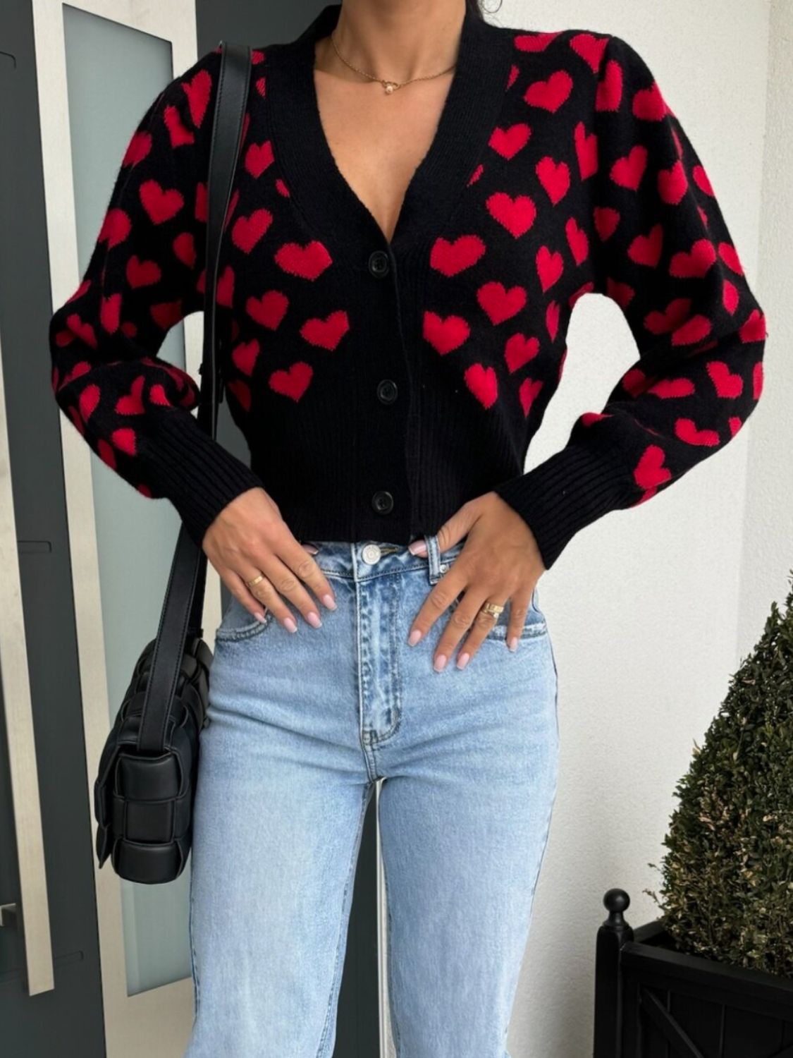 Black knit cardigan with red hearts, puff sleeves, and button front.