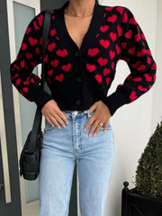 Black knit cardigan with red hearts, puff sleeves, and button front.