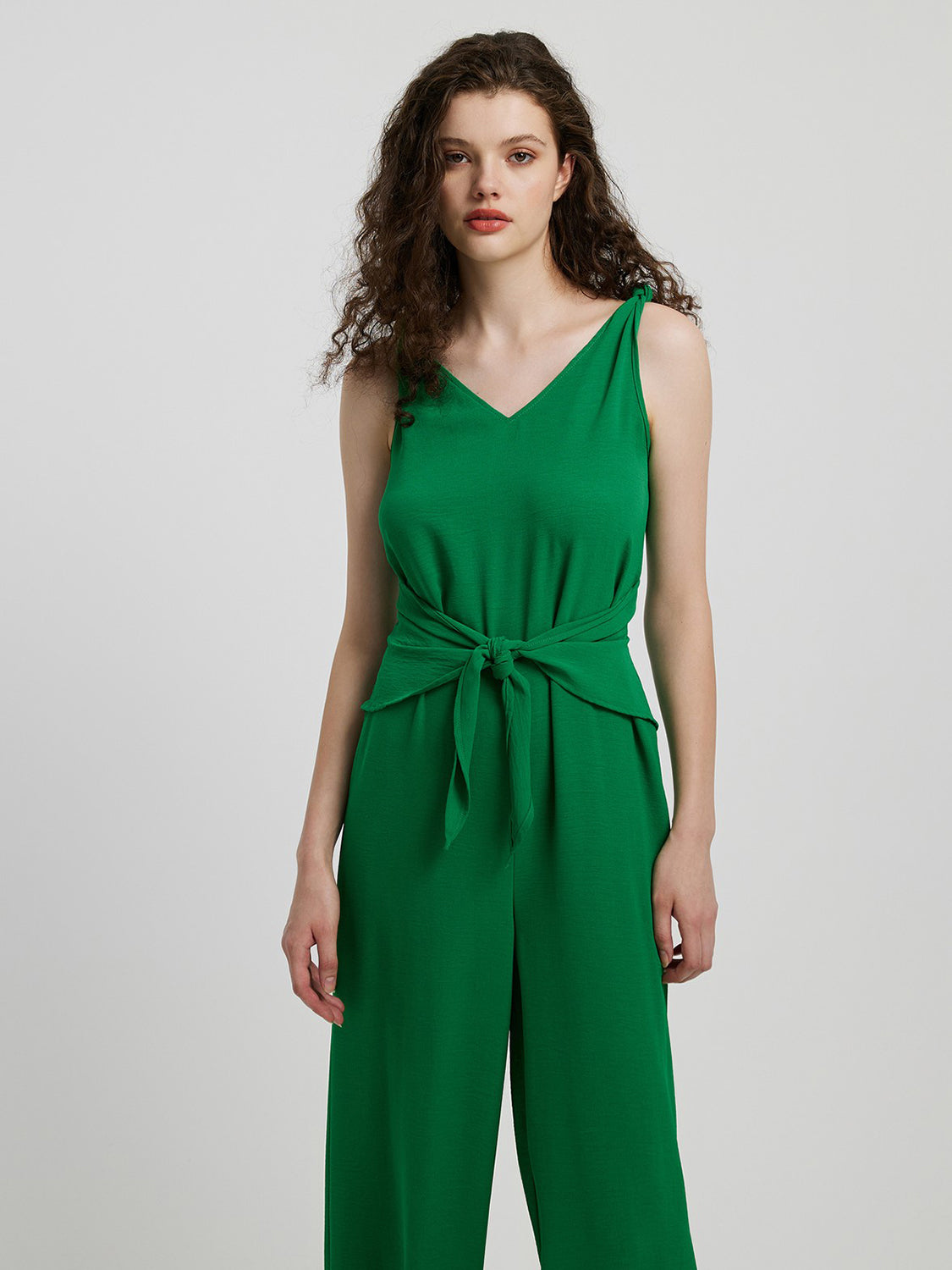 Emerald tie-waist wide leg jumpsuit with V-neck and sleeveless design.