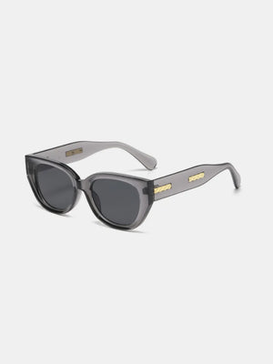 Sculpted cat eye sunglasses in translucent gray with gold accents on the temples.