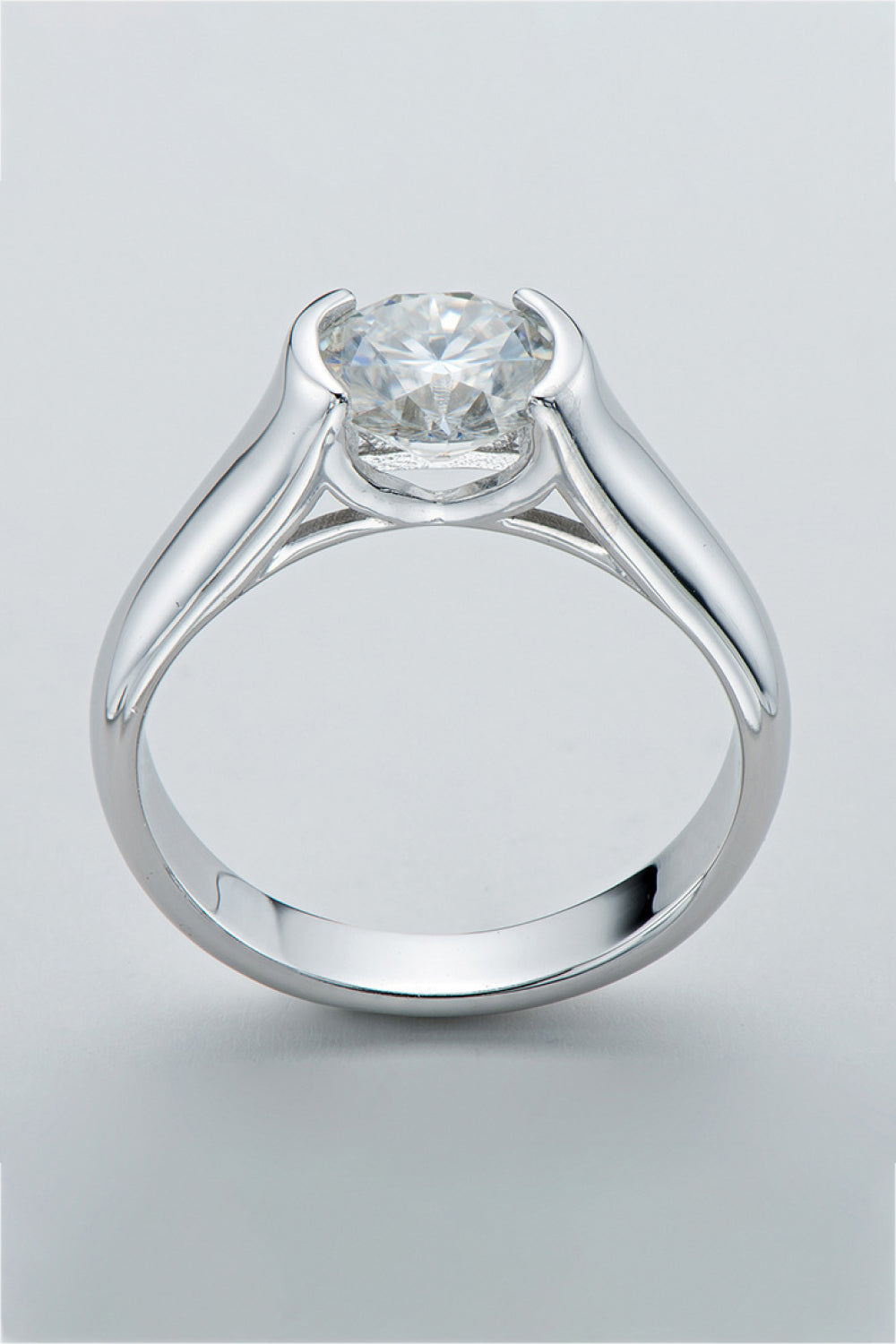 Silver platinum ring with a bezel-set round moissanite solitaire diamond.