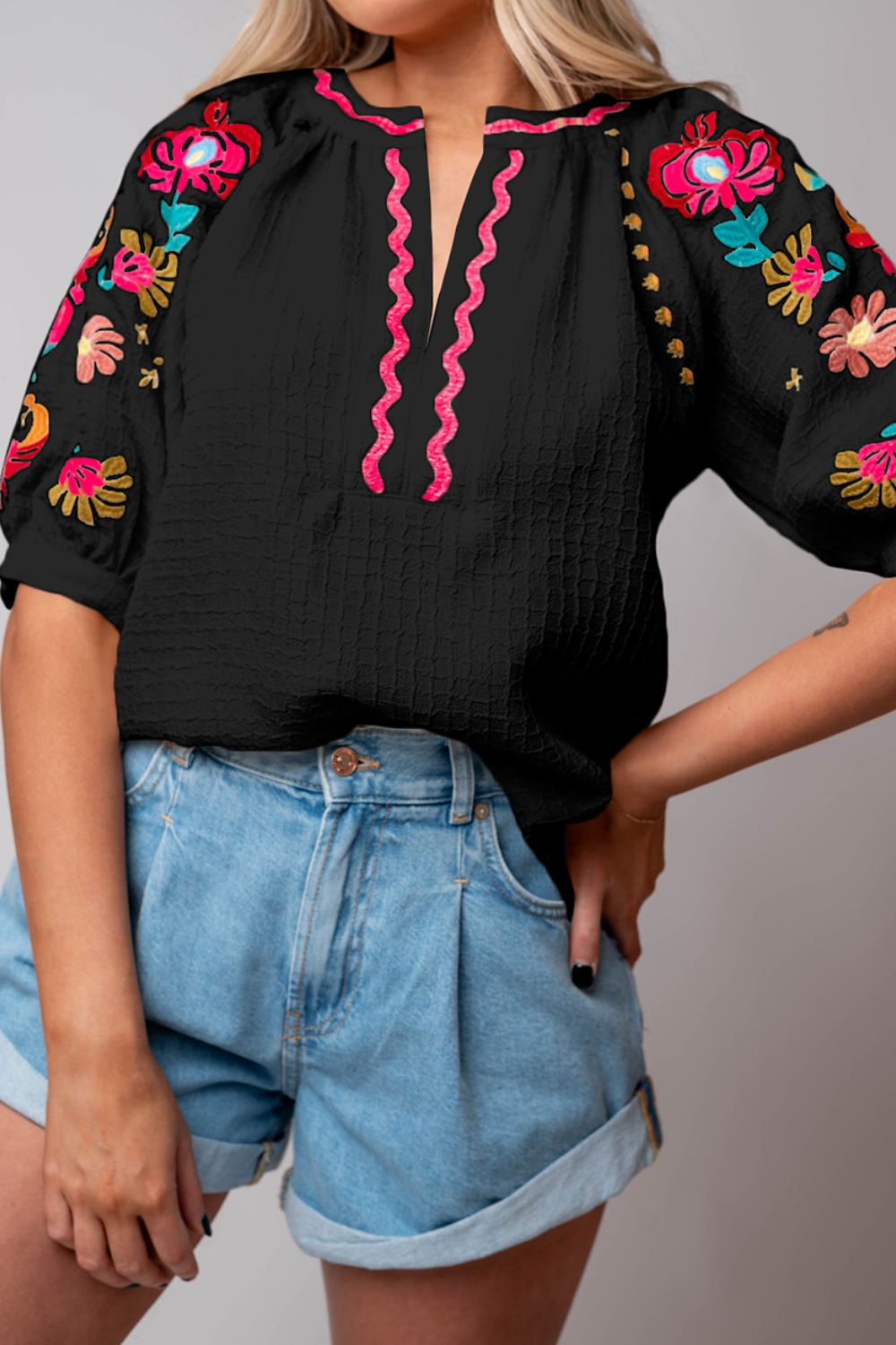 Black embroidered voluminous blouse with pink trim and puff sleeves.