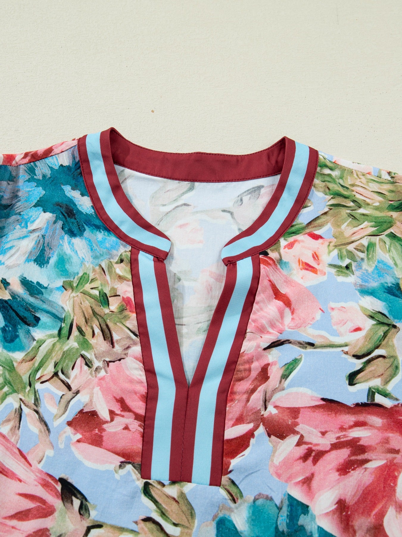 Women's cotton V-neck blouse with a floral print and striped trim detail.