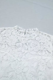 White lace blouse with ruffled mock neckline and floral pattern.