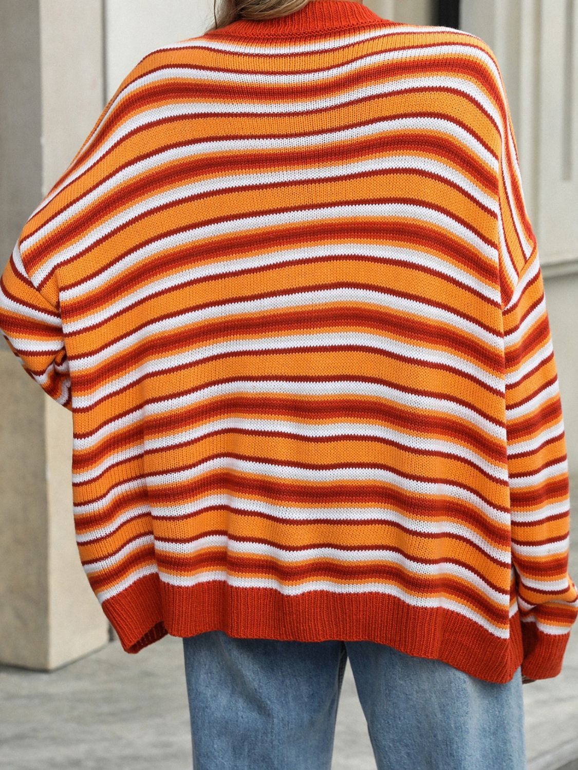 Oversized knit sweater with horizontal stripes in orange, white, and red.