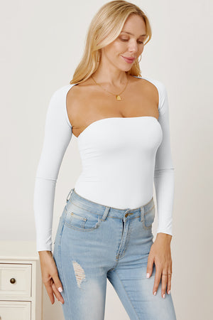 White long sleeve bodysuit with sculpted neckline and open back detail, styled with jeans.
