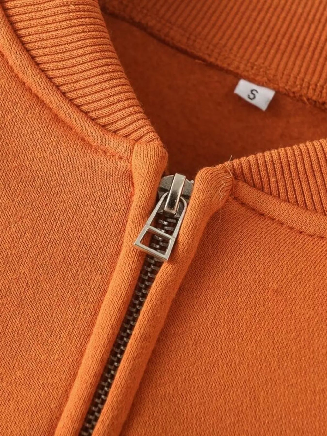 Orange casual zip-up top detail with silver zipper and size S tag.