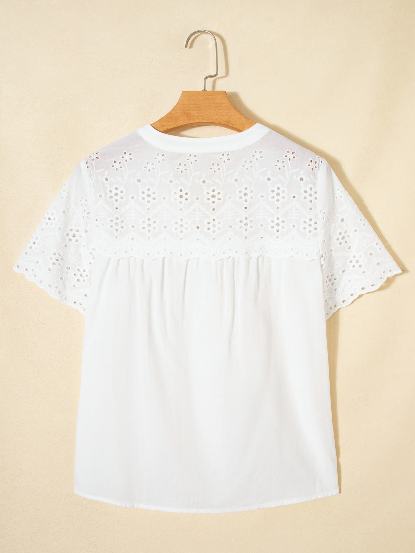 White cotton eyelet embroidered sheer shirt with short sleeves and floral details.