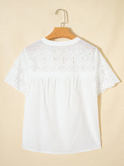 White cotton eyelet embroidered sheer shirt with short sleeves and floral details.