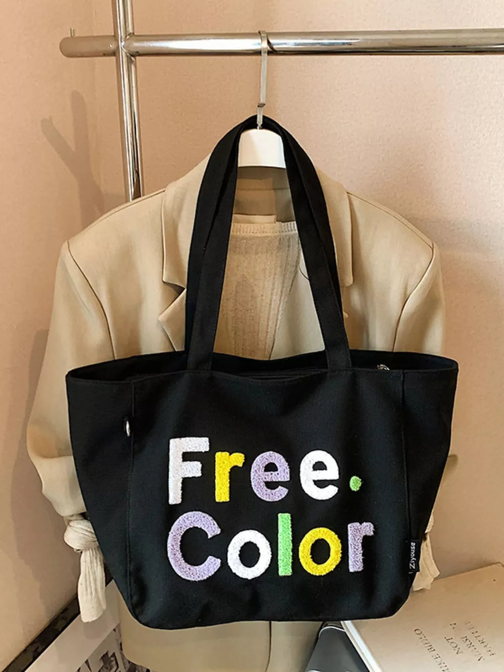 Black canvas shoulder bag with embroidered "Free. Color" text in vibrant letters.