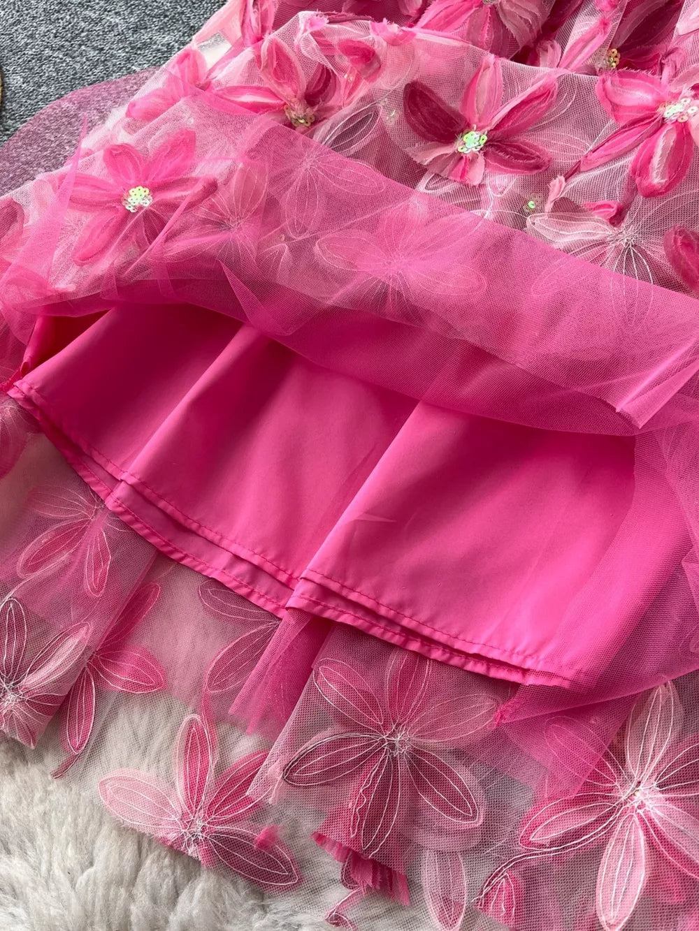 Pink layered skirt with embroidered floral details and a satin lining.