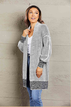 Textured puff sleeve open cardigan in black with a waffle knit pattern and contrast cuffs and hem.