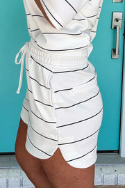 White polyester bikini shorts with black stripes, drawstring waist, and side pockets.