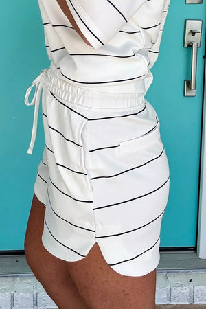 White polyester bikini shorts with black stripes, drawstring waist, and side pockets.
