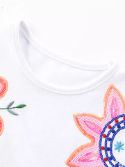 White cotton baby dress with floral embroidery and sequins.