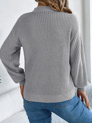 Gray cable knit sweater with cutout detail and balloon sleeves.