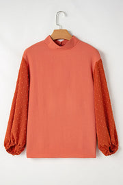 Orange blouson top with mock neck and textured Swiss dot puff sleeves