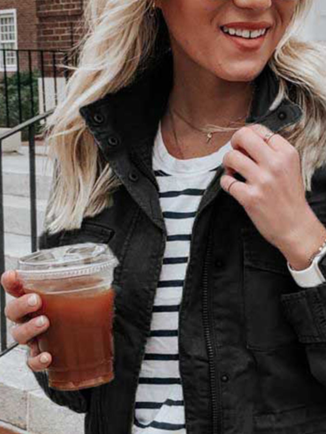 Black utility jacket with zipper and button details, worn over a striped tee.