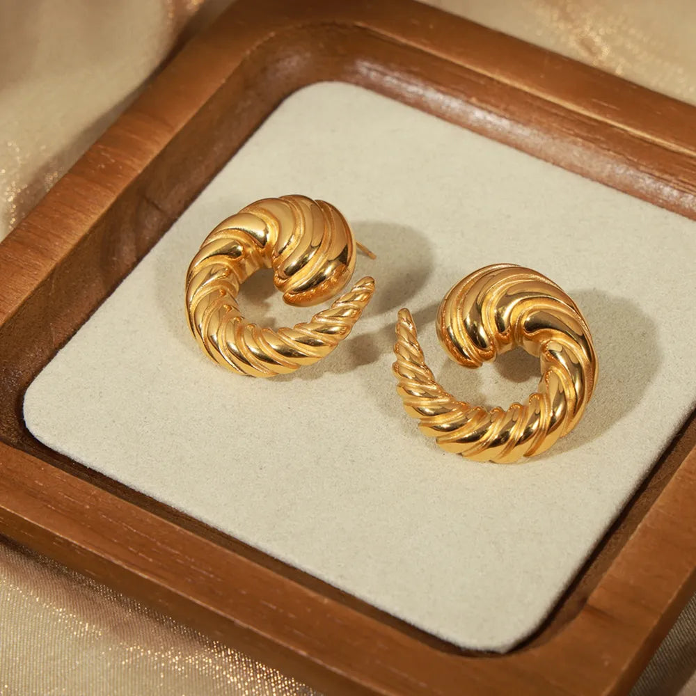 Gold sculptural swirl stud earrings with ribbed texture.