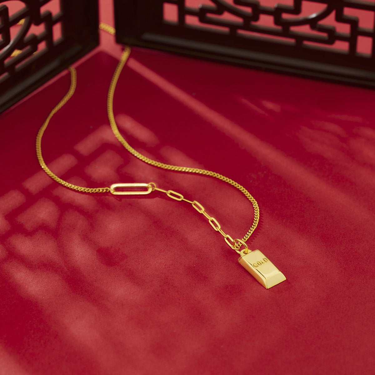 Gold-plated bar pendant necklace with curb links and paperclip chain detail.