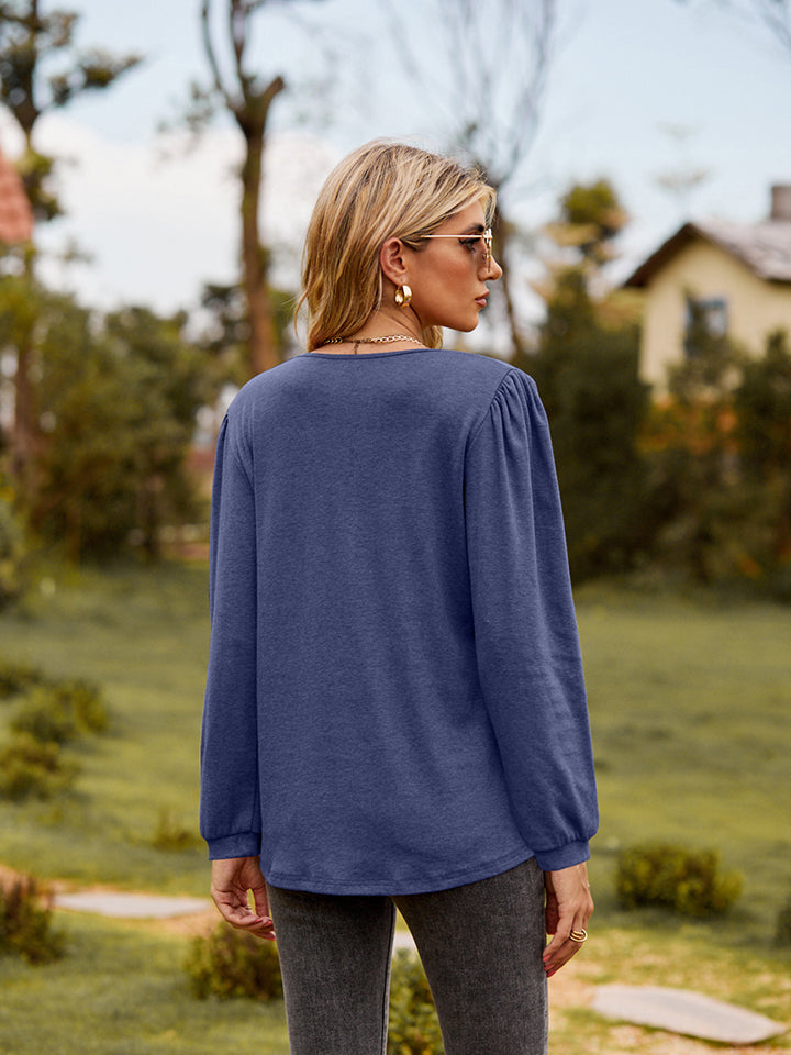 Navy ruffled henley sleeve blouse with gathered shoulders and cuffs.